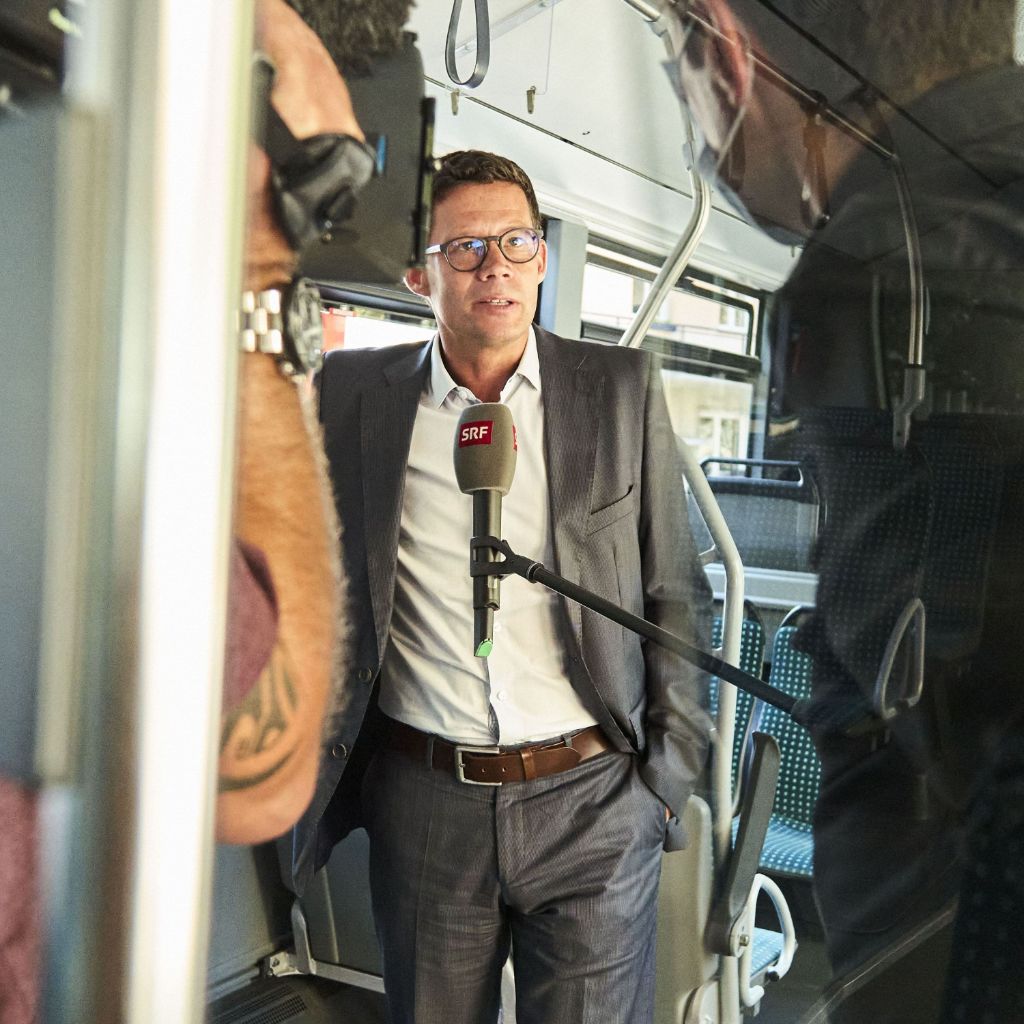 Geschäftsleiter gibt in einem Bus ein Interview an SRF.
