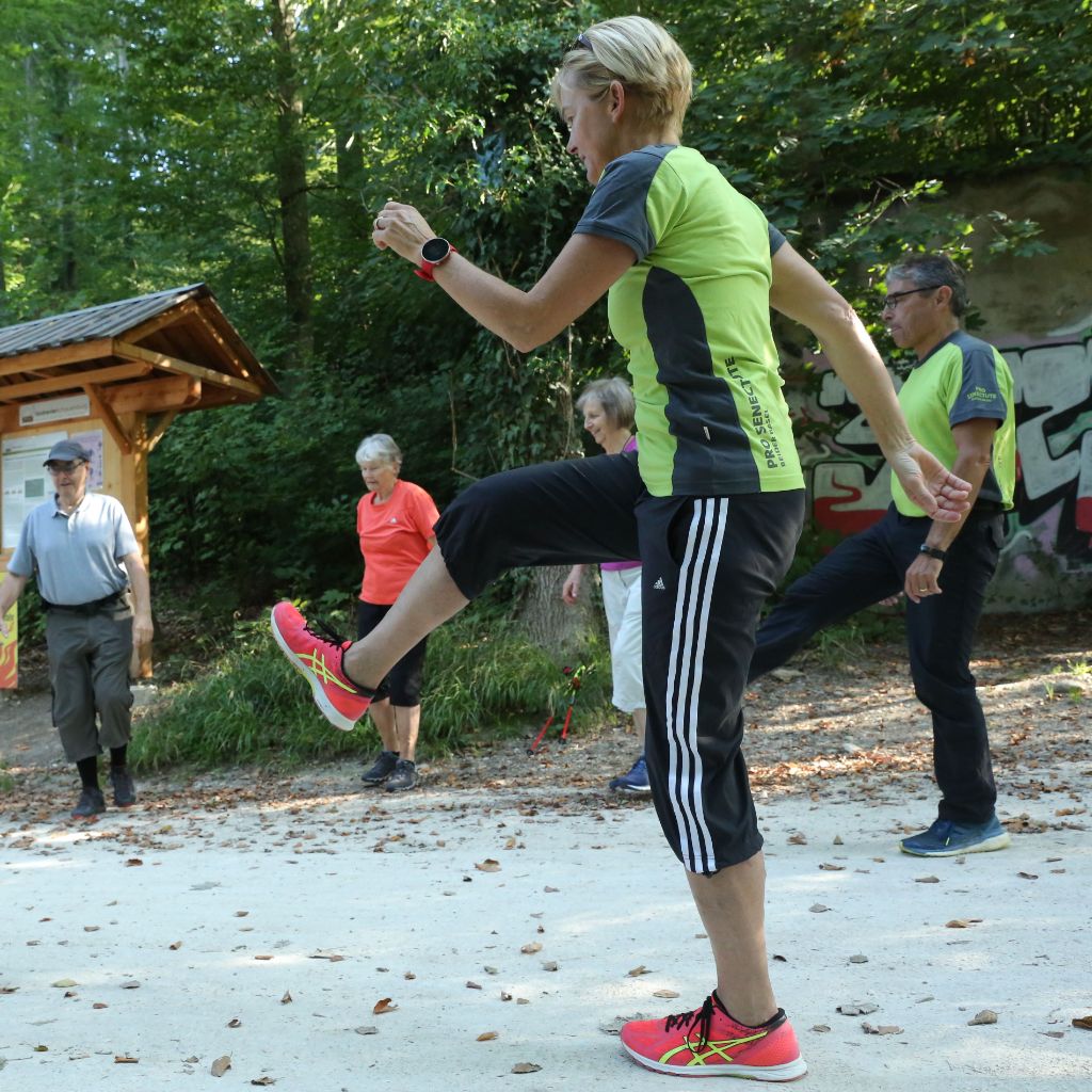 Die Teilnehmenden eines Nordic Walking Kurses wärmen sich unter Anleitung der Betreuer auf.