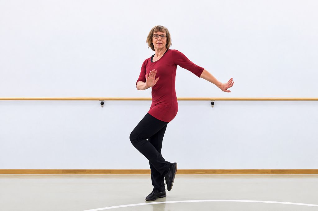 Tanzlehrerin zeigt in einer Turnhalle den Grundschritt des Cha Cha Chas.