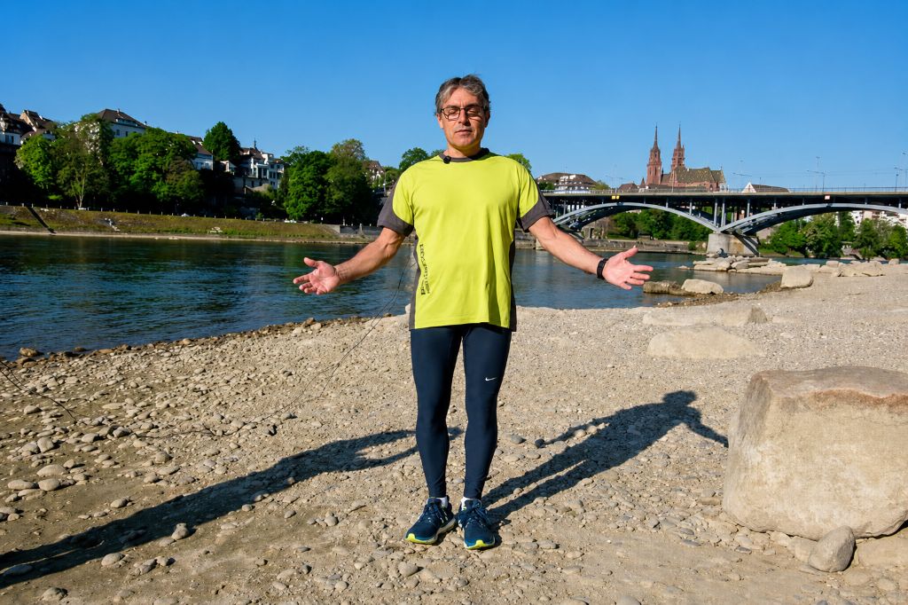 Kursleiter steht erklärend am Ufer des Rheins.