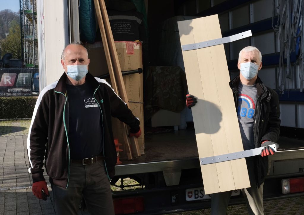 Zwei Männer laden Möbel aus einem Umzugswagen.