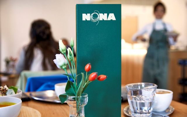 Unsere Menükarte steht im Fokus, Blümchen dekorieren den Tisch.