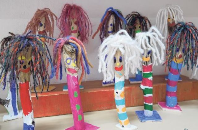 Bunte Holzfiguren stehen in einem Klassenzimmer.