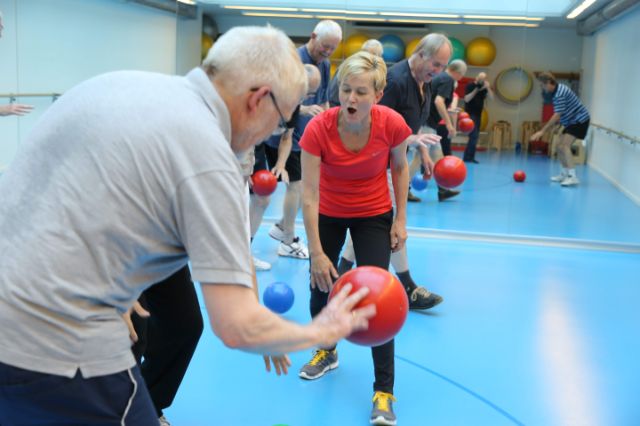 Senioren werden von der Kursleiterin beim Ballspiel motiviert und unterstützt.