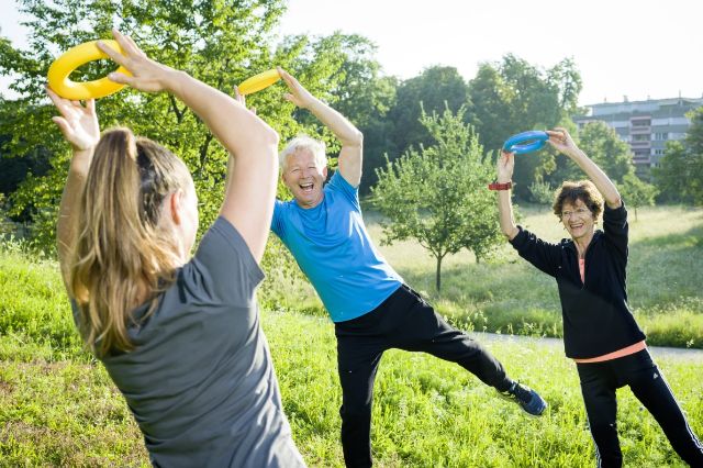 Eine kleine sportliche Gruppe macht Übungen mit Plastikringen im Park.