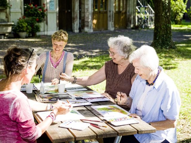 Eine Gruppe von Frauen malt mit Wasserfarben im Park.