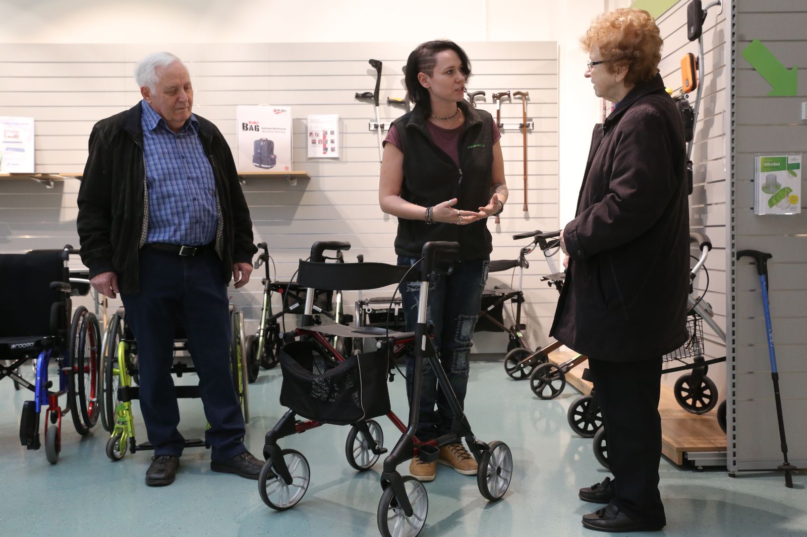 Mitarbeiterin berät älteres Ehepaar bezüglich eines Rollators.